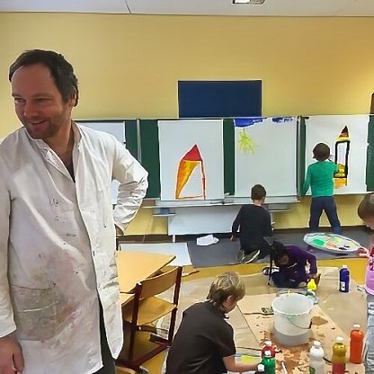 Künstler unterstützt Kinder beim Malen farbenfroher Kunstwerke während eines Kunstworkshops.